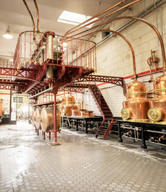 Salle des Alambics de la Distillerie Combier, surplombée d'une structure rouge avec des alambics en cuivre
